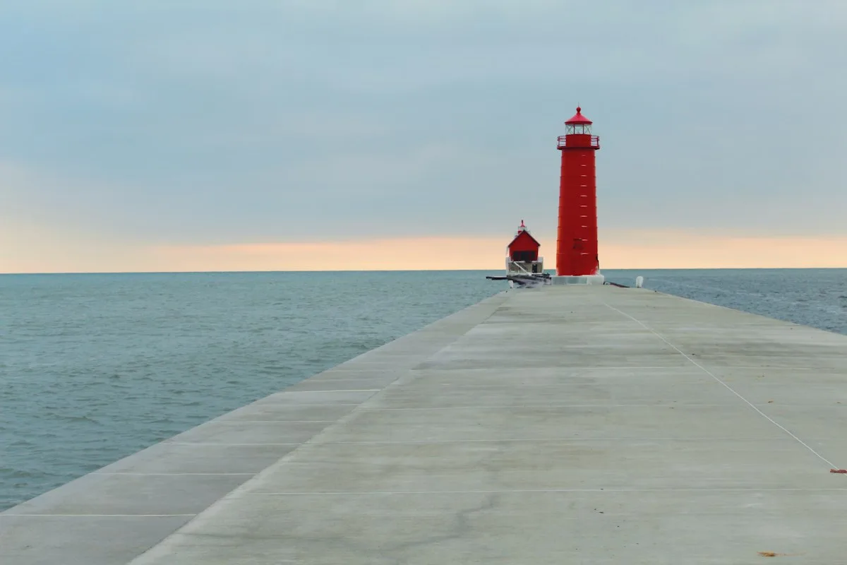 A red lighthouse at the end of a West Michigan pier